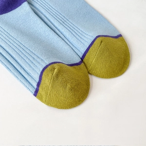 Detail of ribbed cotton socks showing light blue knit with yellow toe and purple stripe
