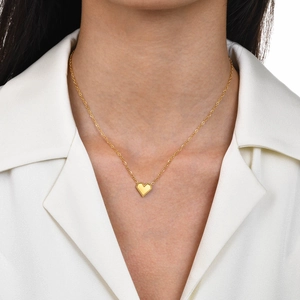 Close-up of gold heart pendant necklace on model with white shirt background