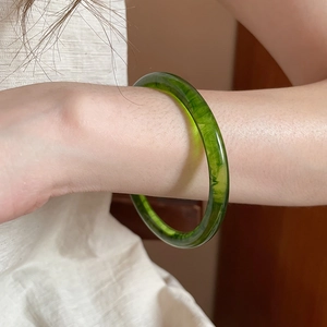 Detailed view of a translucent green resin bangle with natural flow patterns on wrist