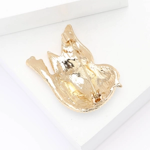 Detailed back view of golden alloy pigeon brooch showing safety pin and hinge mechanism