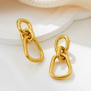 Detail of chunky gold triple-link earrings with high-polished finish on white background
