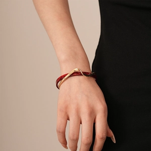Detail of red marble resin bangle with gold-plated geometric inlay worn by a model