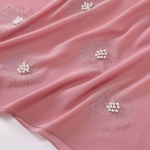 Close-up of pink chiffon hijab featuring intricate rhinestone flower and pearl bead details