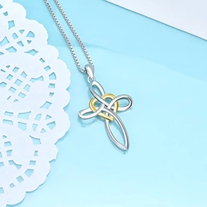 Detail of silver and gold heart cross pendant on a delicate box chain necklace