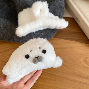 Detailed view of a white plush seal hair claw clip featuring black spots and round eyes