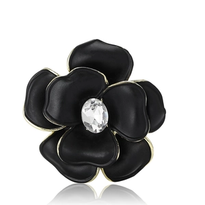 Elegant black enamel flower brooch with gold edges and crystal center on white background
