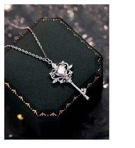 Macro shot of heart-shaped iridescent gem key pendant on a green velvet jewelry box