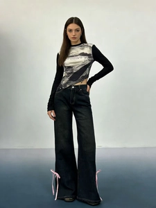 Dettaglio jeans grigio scuro a gamba larga con fiocchi rosa e orlo irregolare