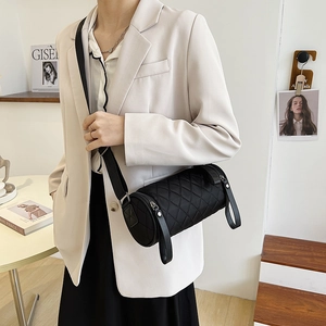 Chic black quilted cylinder crossbody bag with adjustable strap shown on model outdoors