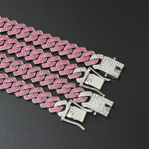 Three iced-out Cuban link chains with pink and white rhinestones on black background
