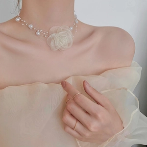 Detail of white organza rose choker with delicate pearl strands on a model neck