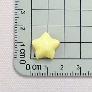 Macro shot of a 1.5cm yellow resin star bead on a green cutting mat for DIY jewelry