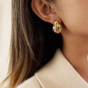 Macro shot of ladybug stud earring with colorful crystals on a model's ear