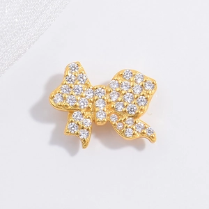 Elegant gold bow pendant with sparkling white cubic zirconia in high detail on white fabric