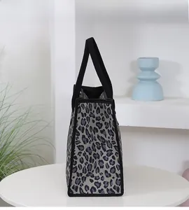 Detail view of the spacious leopard print tote bag with black durable handles on a table
