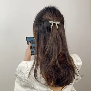 Detailed view of silver bow hair clip with sparkling rhinestones on long brown hair
