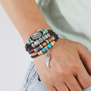 Detail eines mehrlagigen Lederarmbands mit Ethno-Perlen und Federanhänger im Retro-Stil