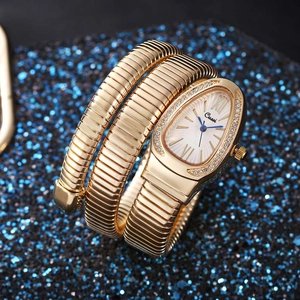 Macro shot of gold snake-shaped wrap watch with zircon bezel on blue glitter