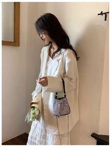 Fashion model with black rhinestone bucket bag, white blazer and lace dress