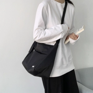 Neutral black canvas messenger bag worn by model with large capacity and urban style