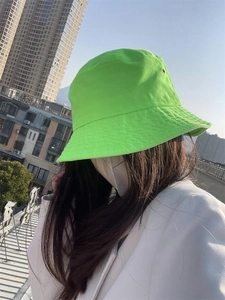 Close-up of bright green cotton bucket hat worn by model on urban rooftop background