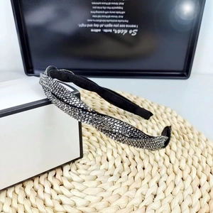 Detail of a braided black headband with sparkling gray rhinestones on a woven straw mat