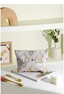 Detail of vintage jacquard makeup bag with floral embroidery and brand label on a desk