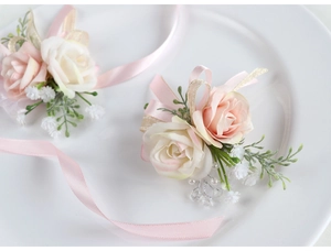 Vista dettagliata del corsage da polso con rose artificiali rosa e avorio su piatto bianco