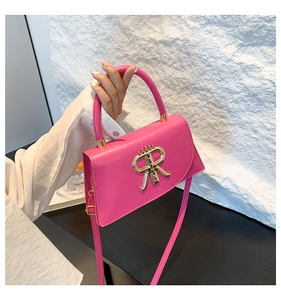 Pink PU leather tote bag with gold R logo and handle held against white textured wall