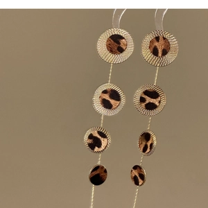 Detailed close-up of Bohemian gold-plated earrings with layered leopard print round charms