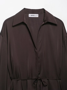 Detail of dark brown satin shirt collar with branded label and smooth fabric texture