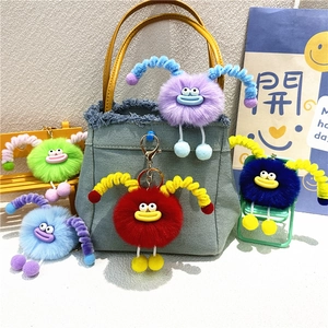 Cute plush monster keychains with sausage lips in various colors on denim bags and chairs