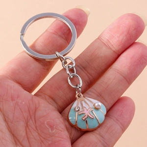 Detailed close-up of a blue shell keychain featuring a pink starfish and pearl accents