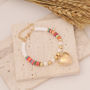 Bohemian style bracelet with colorful clay discs, pearls, and a large golden heart charm