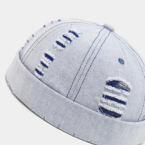 Detail of light blue denim docker hat showing distressed ripped texture and stitching