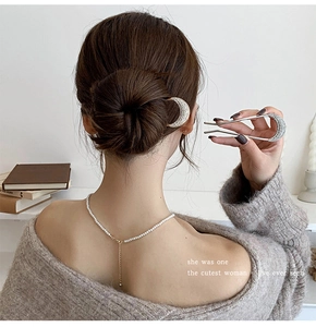 Detail of moon-shaped pearl hair pin secured in a bun hairstyle for elegant styling