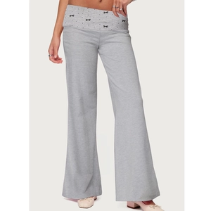 Detail of grey wide-leg trousers featuring a folded waist and black polka dot bow design