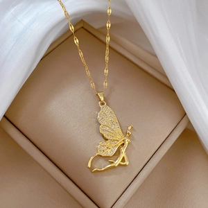 Detailed view of a gold angel pendant necklace with sparkling wings on a beige jewelry box