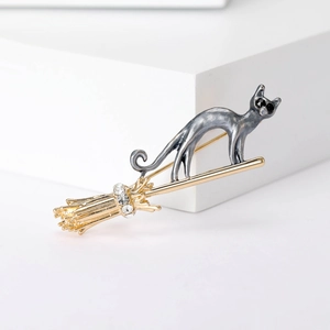 Detailed close-up of a cat riding a broom brooch with gold finish and rhinestones