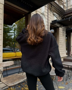 Outdoor back view of a black warm fleece jacket with fuzzy lamb wool texture finish