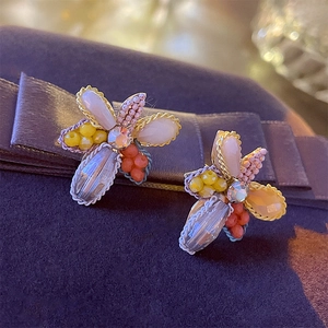 Détail des boucles d'oreilles fleurs faites main avec perles sur ruban de soie