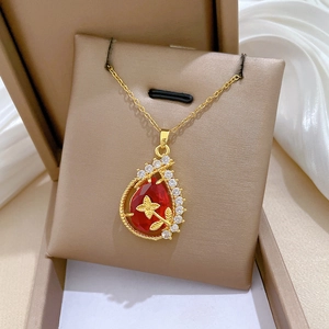 Close-up of golden teardrop necklace with red gemstone and white silk background