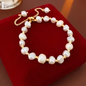Elegant baroque pearl bracelet with gold metal beads and adjustable chain on red velvet