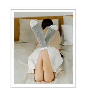Detailed view of gray coral fleece socks worn in a cozy bedroom setting for winter warmth