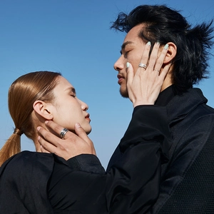 Minimalist silver angel feather rings for couples shown against a clear blue sky background