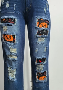 Detailansicht der Jeans mit Halloween-Flicken wie Kürbis und Totenkopf in den Rissen