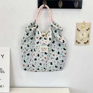 Detailed macro of blue textured tote bag featuring cat prints and woven rope handles