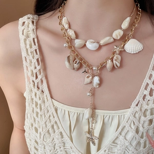 Detail of layered gold necklace with natural seashells, pearls, and a starfish pendant
