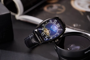 Detail of tonneau mechanical watch with blue dial, skeletal flywheel and leather strap