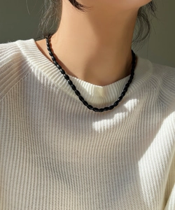 Close-up of minimalist black onyx beaded necklace with oval beads on a knit sweater